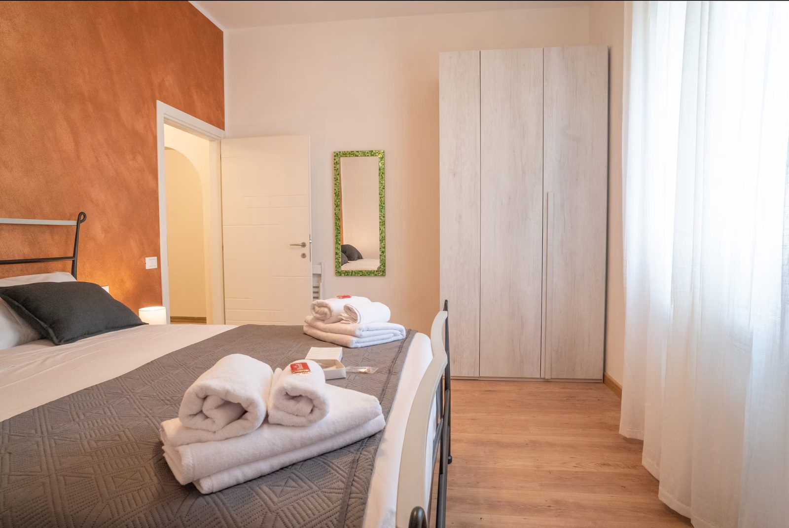 The sunset-coloured wall of the Tramonto room, behind the bed